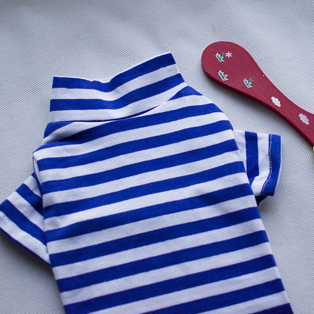 Blue and white striped fabric with a red spoon and yellow bird toy on a gray background