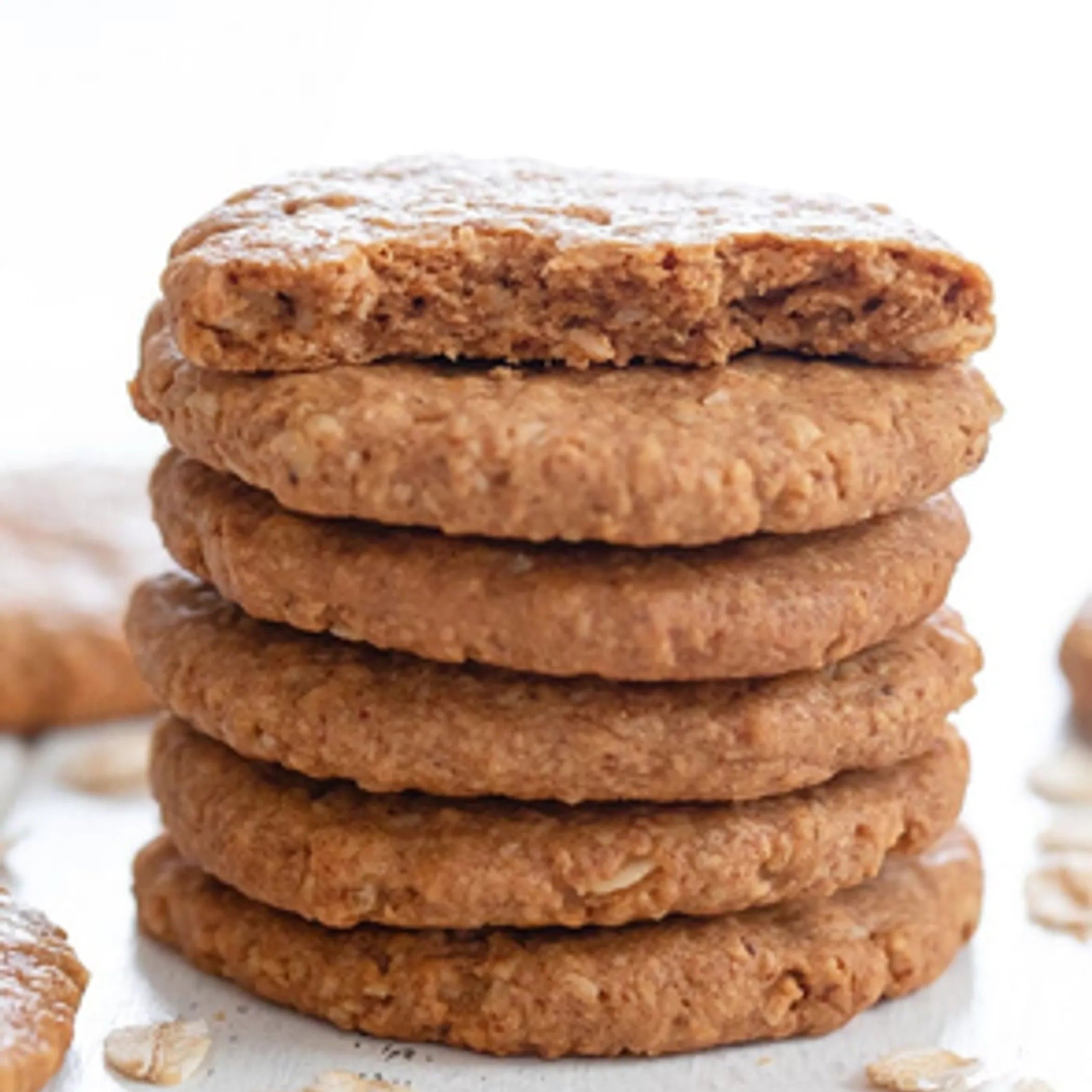 Stack of oatmeal cookies on a white surface with blurred background