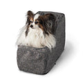 Small dog sitting in a gray pet bed on a white background