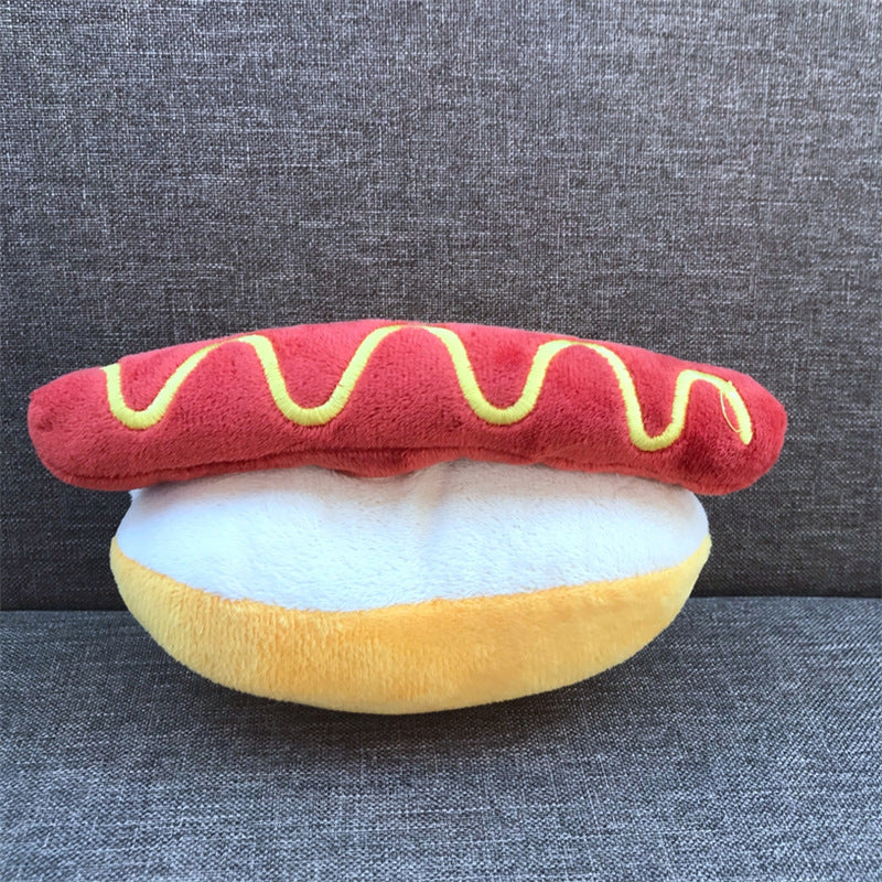 Plush toy shaped like a hot dog with mustard on a gray background