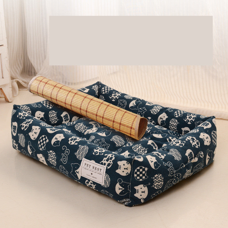 Blue pet bed with white patterns on a light surface, featuring a rolled-up bamboo mat.