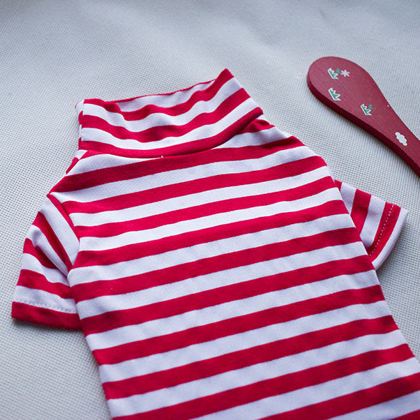 Red and white striped shirt on a light gray surface with a wooden spoon and yellow object.