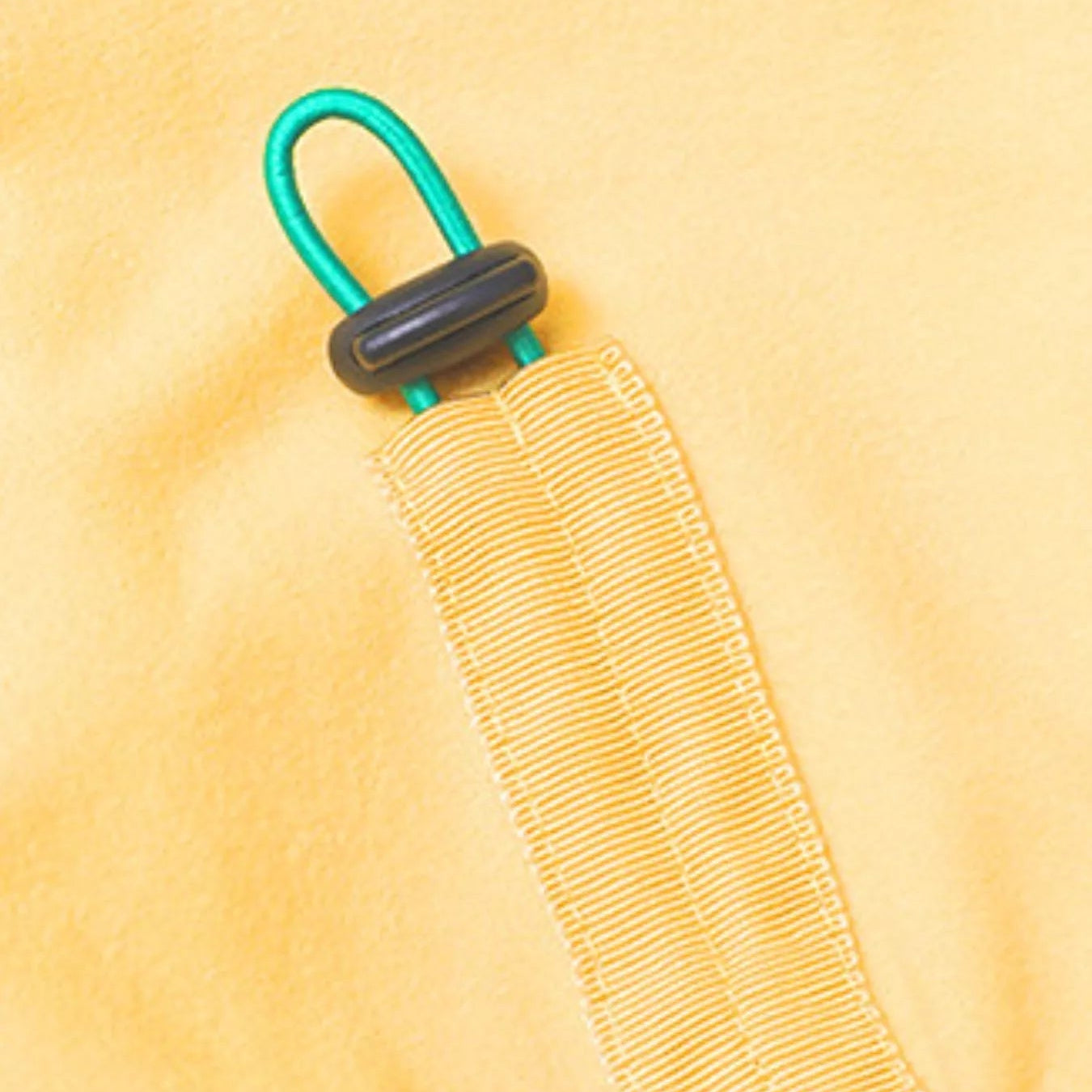 Close-up of a yellow fabric with a green and black buckle on a yellow background