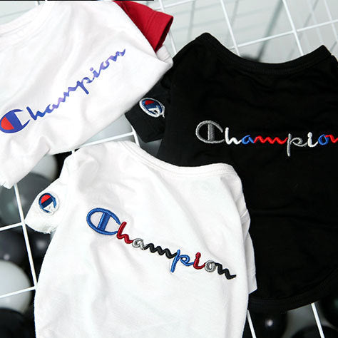 Three Champion t-shirts in black, white, and red on a grid background