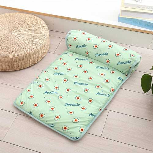 Green quilt with avocado pattern and matching pillow on a wooden floor.