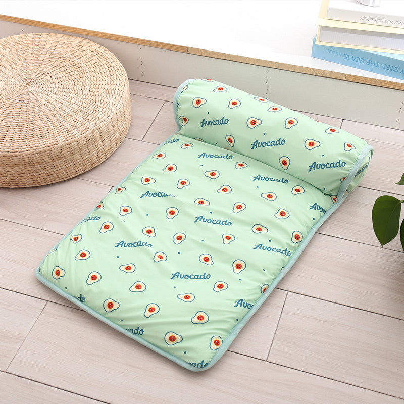 Green quilt with avocado pattern and matching pillow on a wooden floor.