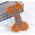 Dog toy shaped like a bone with brown and orange texture on a marble surface.