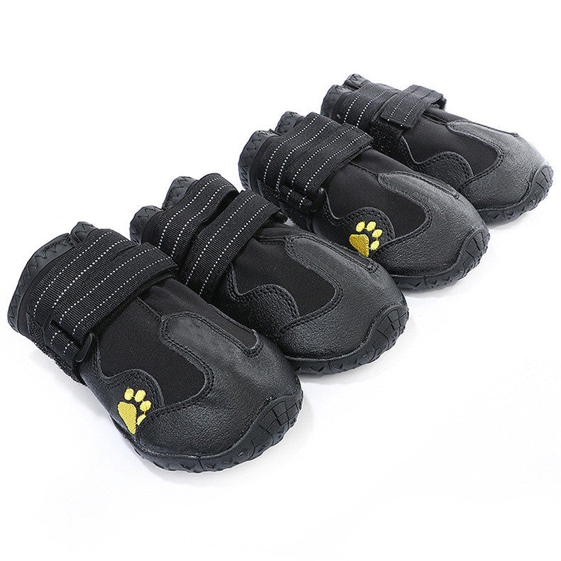 Set of black pet boots with yellow paw prints on a white background