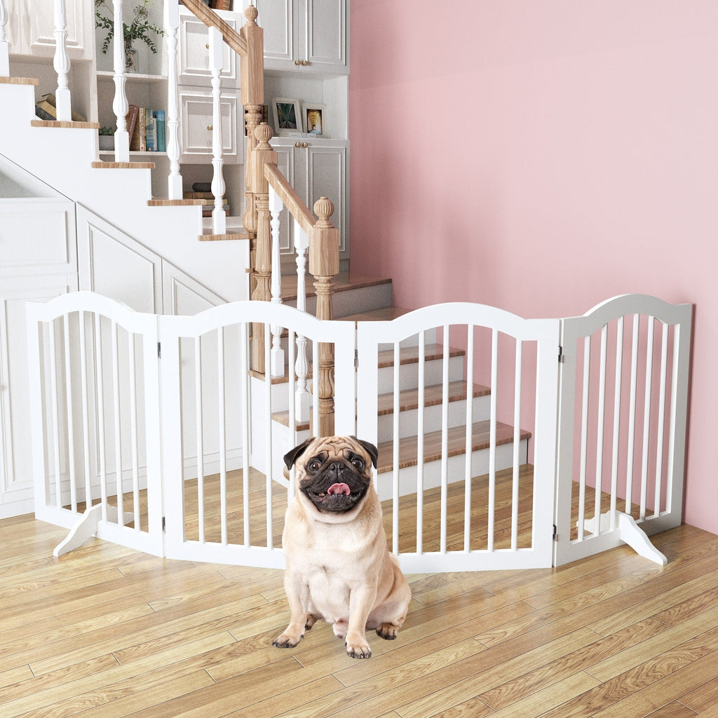Pug sitting in front of a white pet gate in a home setting with pink walls and wooden staircase.