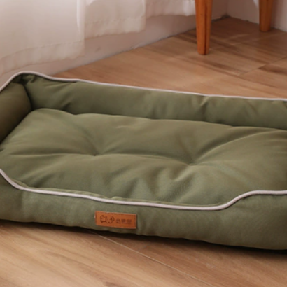 Green pet bed on a wooden floor with a white wall in the background