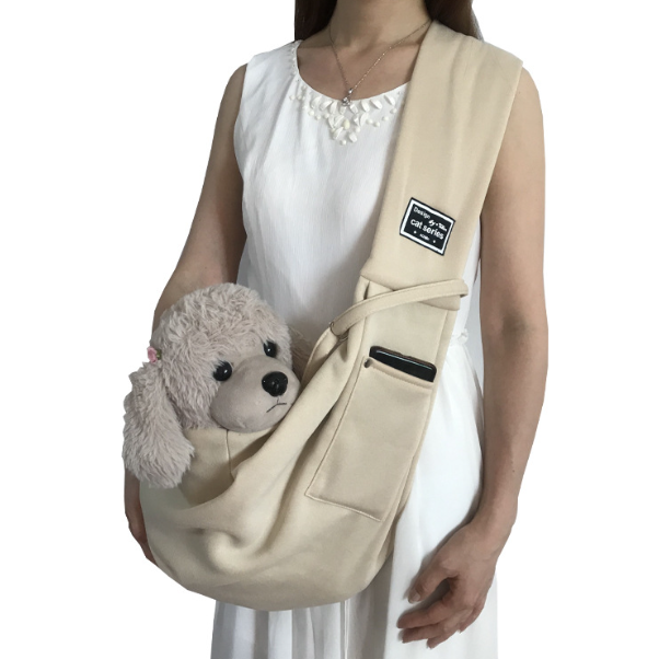 Person holding a beige pet sling with a small white dog inside, on a white background