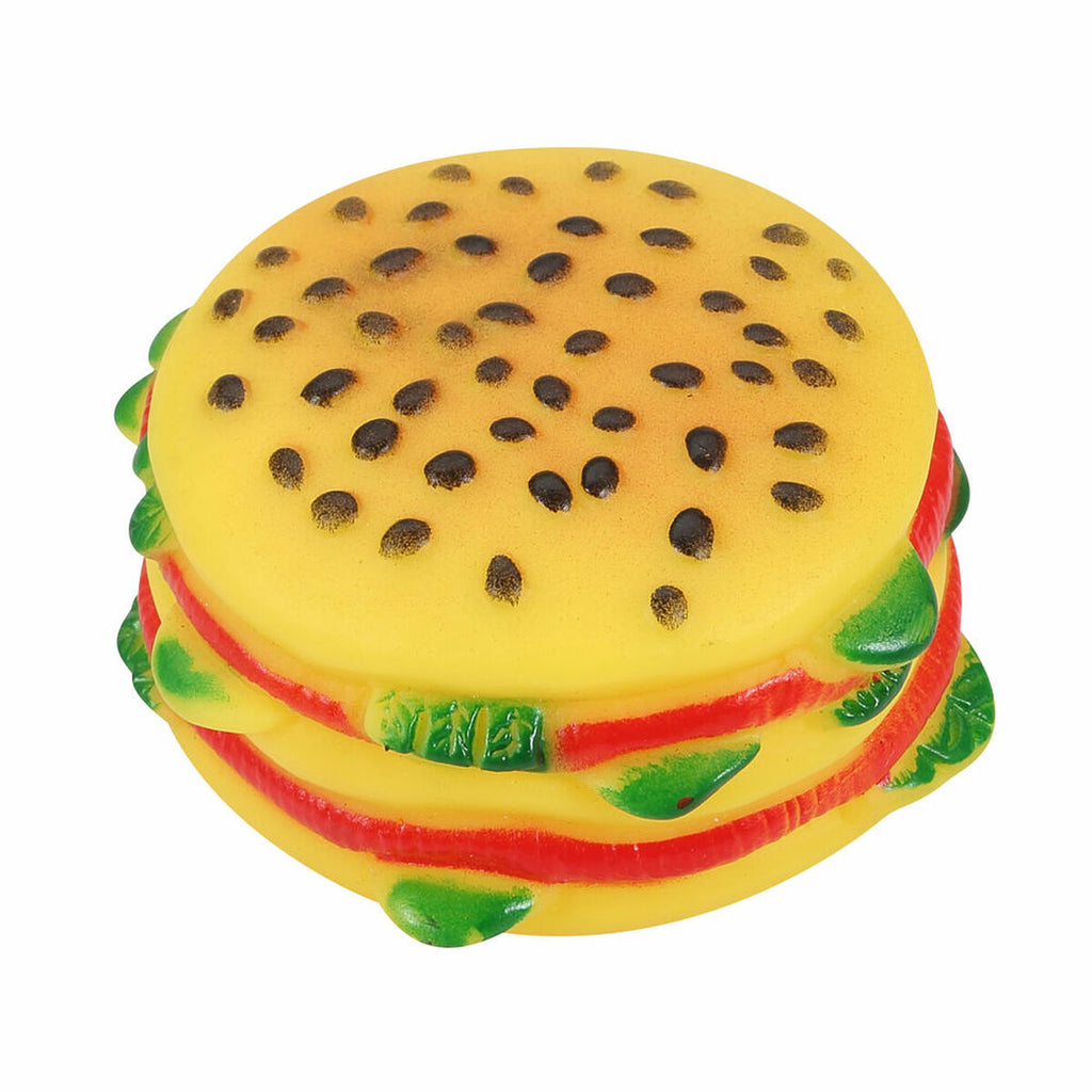 Toy resembling a hamburger with yellow bun, red sauce, and green leaves on a white background