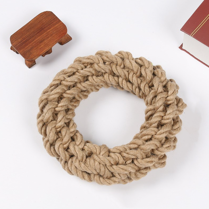 Knitted beige wreath on a white background with a small wooden stool and book.