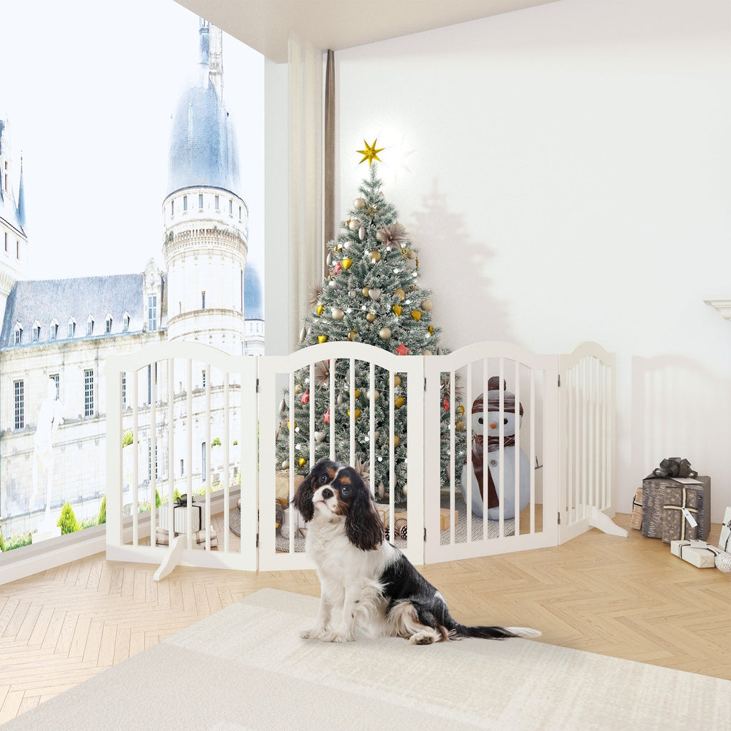 Two dogs sitting inside a white pet gate with a Christmas tree in the background.