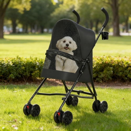 Dog in a black stroller on a grassy area with trees in the background