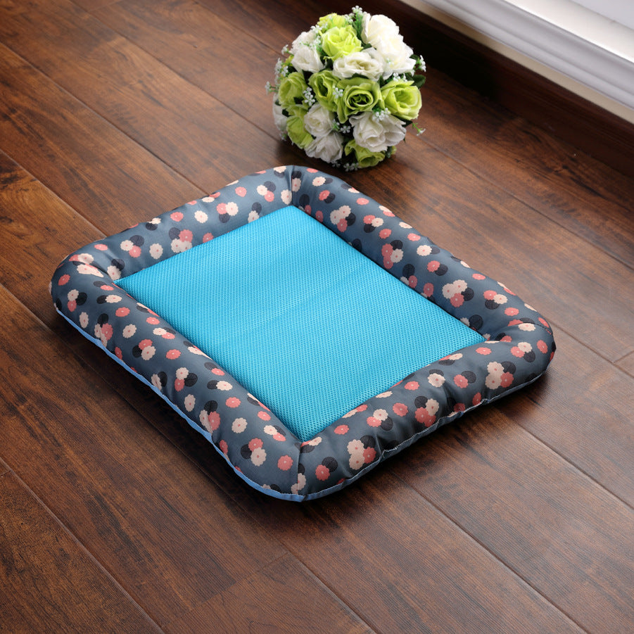 Floral-patterned pet bed with a blue interior on a wooden floor, accompanied by a small bouquet of flowers.