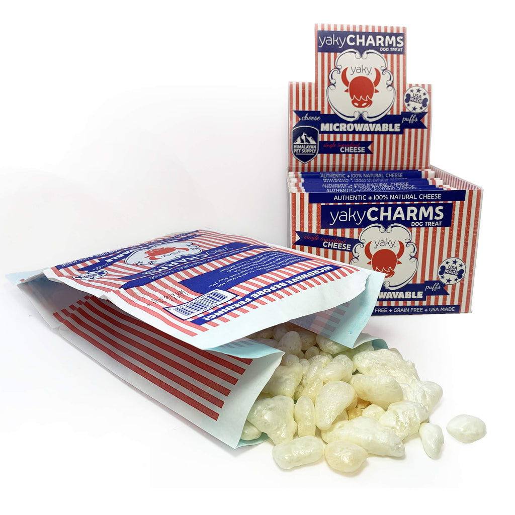 Yaky Charms cheese puffs in a red and white striped packaging with a box in the background.