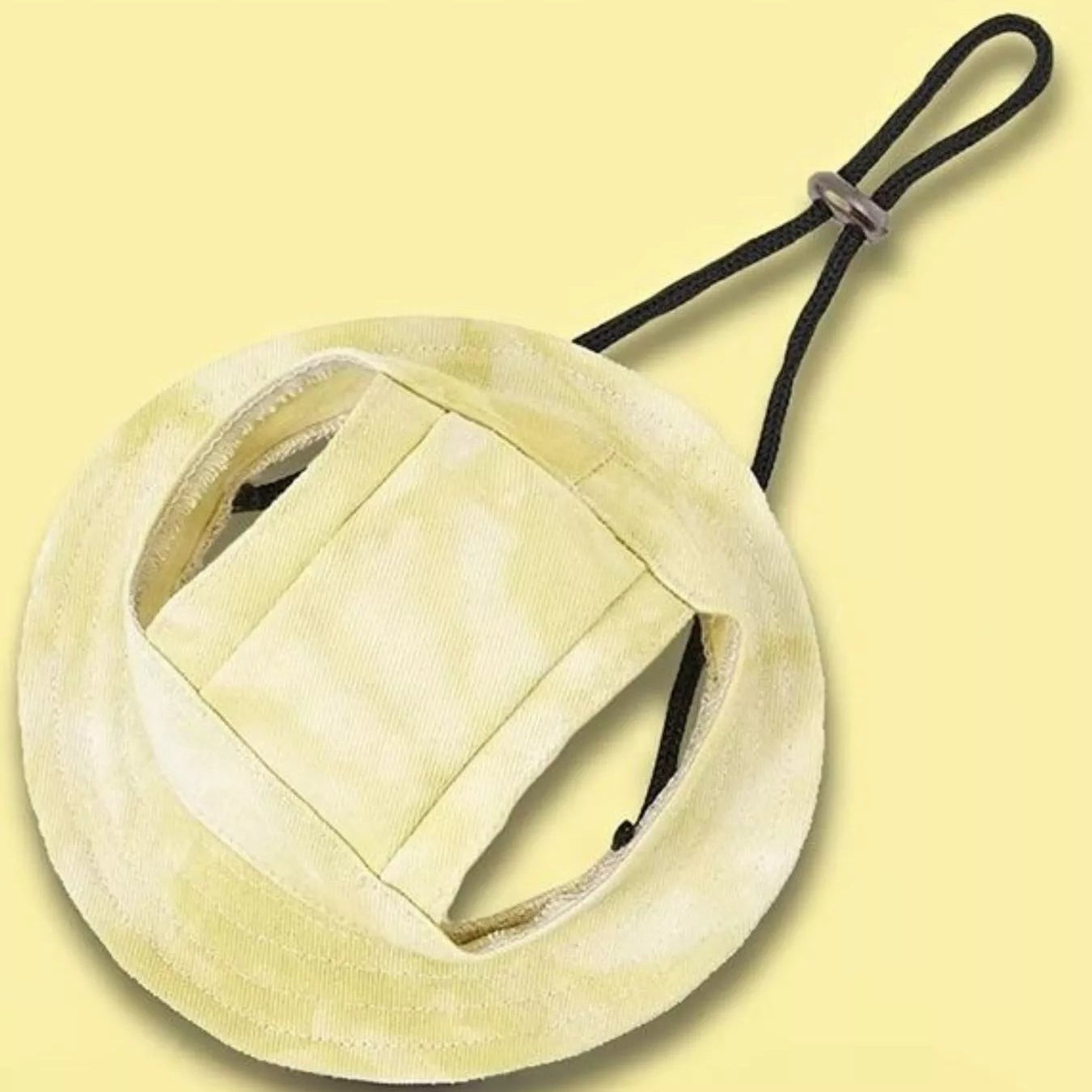 Round beige object with a black strap on a light yellow background
