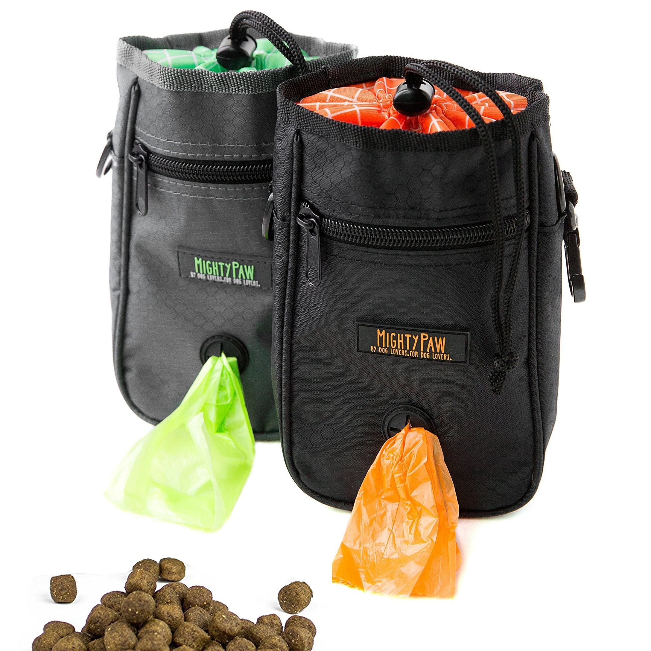 Two black pet training clickers with Mighty Paw branding, accompanied by dog treats and plastic bags.