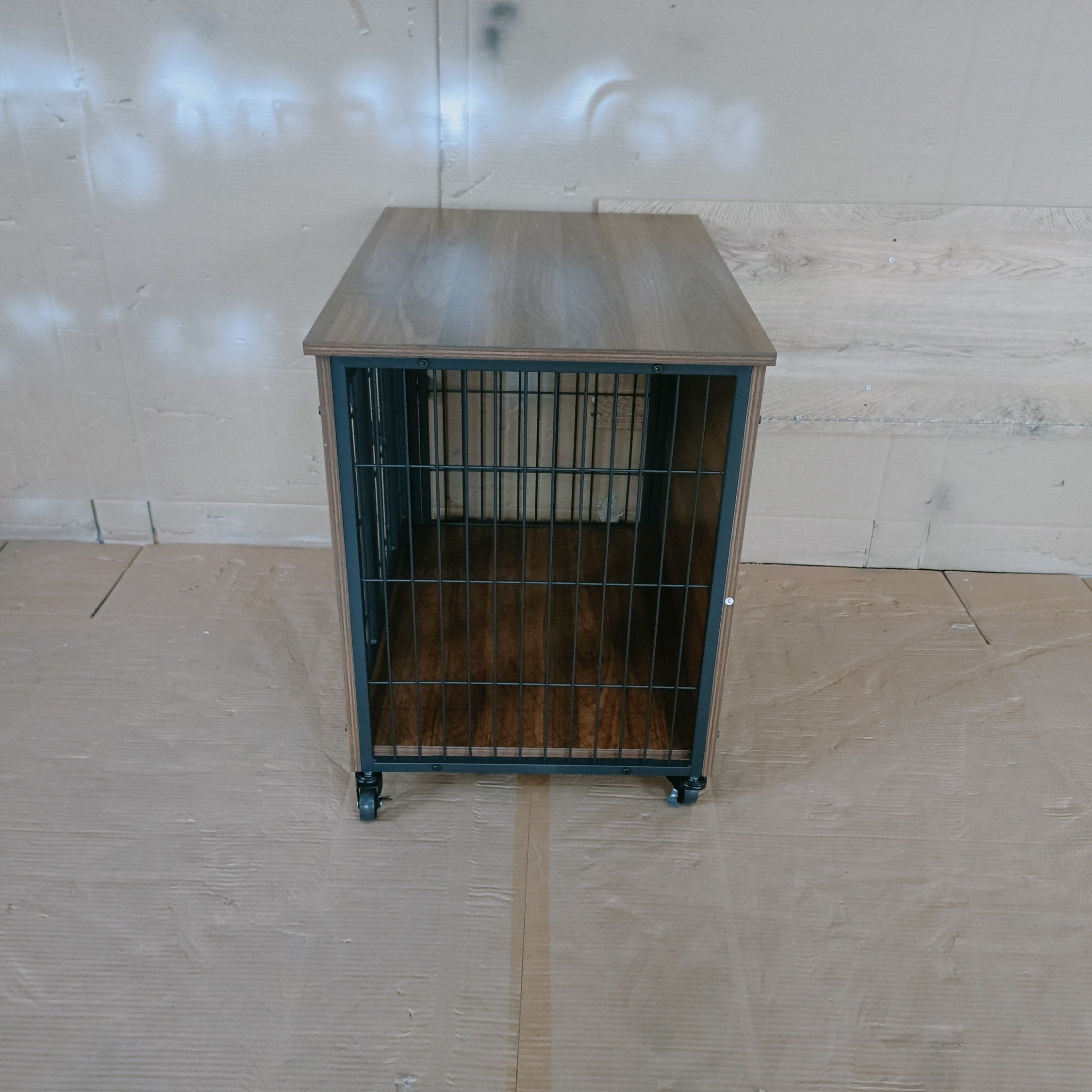 Metal cage on wheels against a plain wall with a tiled floor.