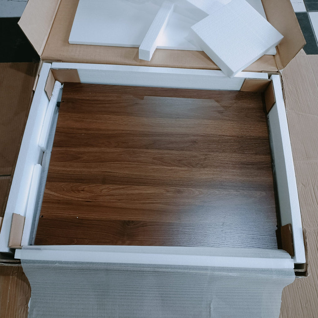 Open cardboard box with wooden floor model inside on a checkered floor.