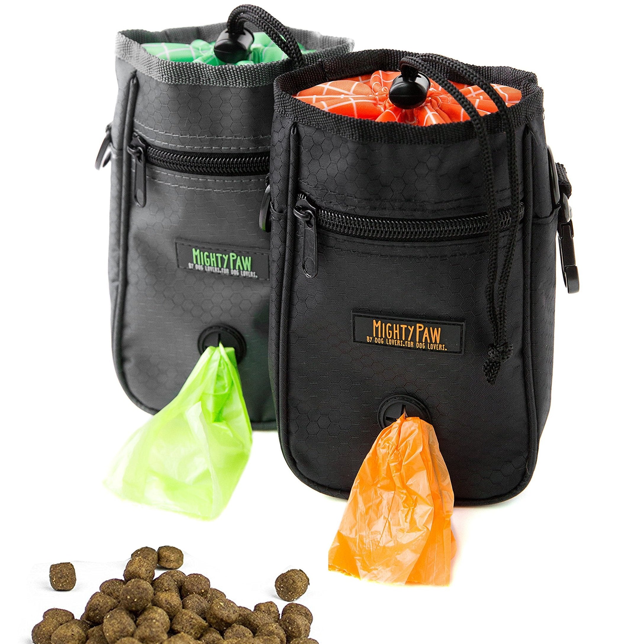 Two black pet training clickers with Mighty Paw branding, accompanied by dog treats and plastic bags.
