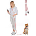 Woman holding a pink dog leash with a dog sitting next to her on a white background