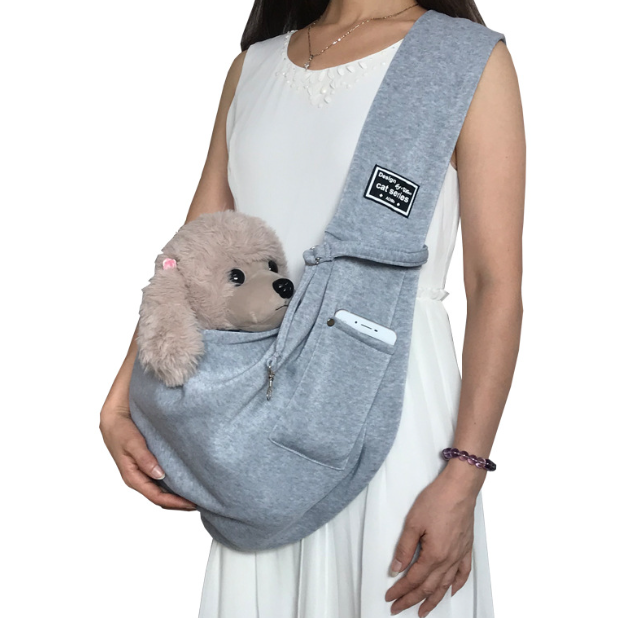 Person holding a small dog in a gray pet sling against a white background