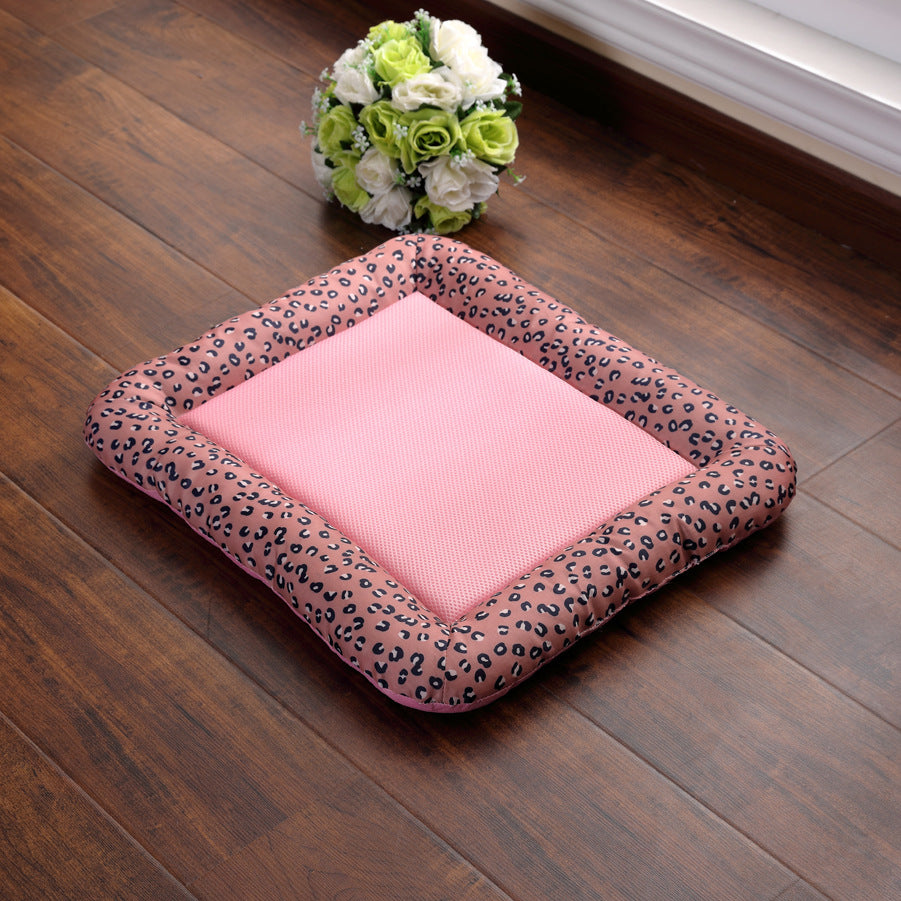 Pink pet bed with leopard print border on a wooden floor, accompanied by a small bouquet of flowers.