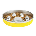 Yellow pet bowl with stainless steel interior filled with kibble and three silver dog toys on a white background.